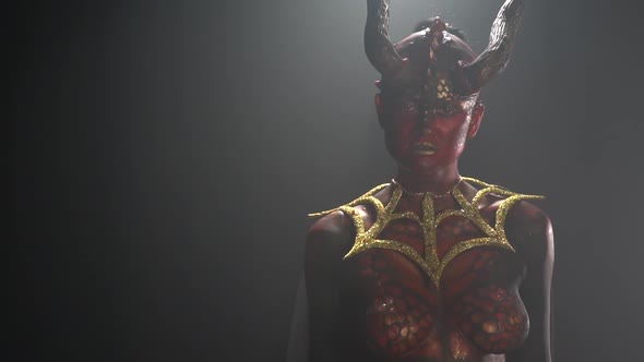 Demon with big horns and red eyes, wearing golden armor is looking