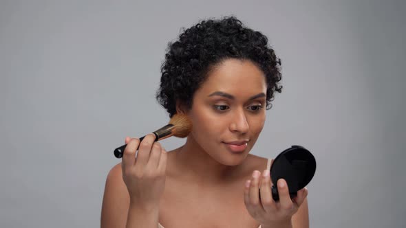 Woman with Mirror and Brush Applying Make Up