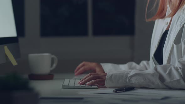 Young asian woman working late using desktop on desk in living room at home