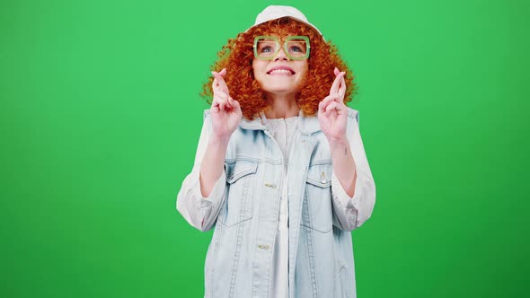 Young Funny Redhead Curly Woman in Glasses and Panama Hat Making Cherished Wish Crossing Fingers