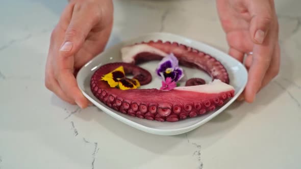 Slow motion footage of a plate of octopus tentacles being gently set on a table