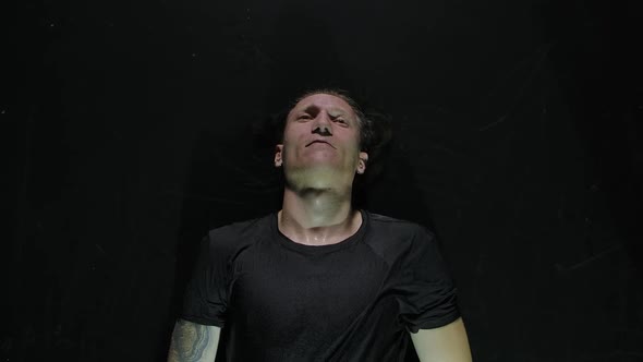 Top View of the Leader of a Rock Band Lies on the Water Surface in a Dark Studio