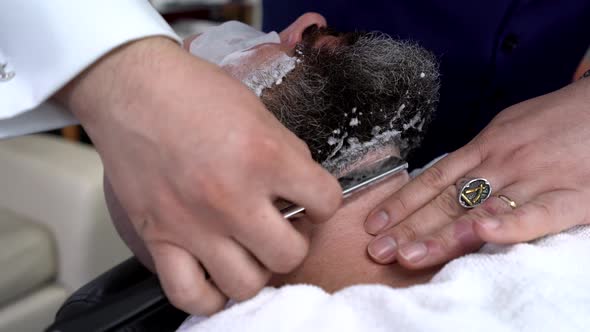 Male barber shaving client in salon