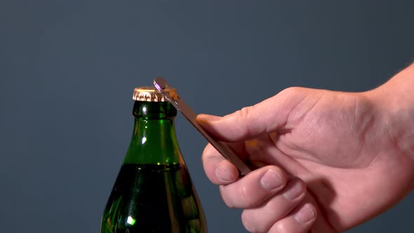 Man Opens Bottle with Fizzy Drink with a Special Opener. Glass Bottle with Metal Lid