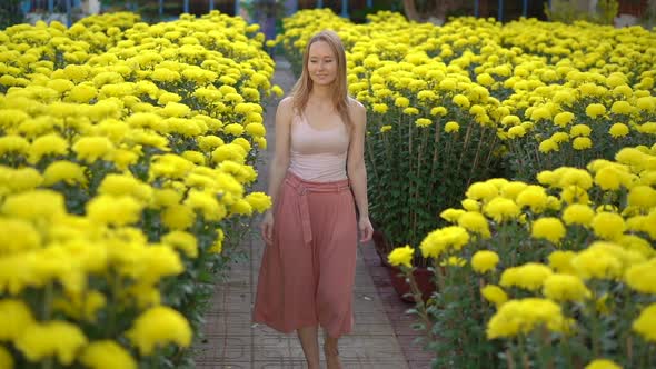A Young Woman Walking Among Lots of Yellow Flowers That East Asian People Grow To Celebrate a Lunar