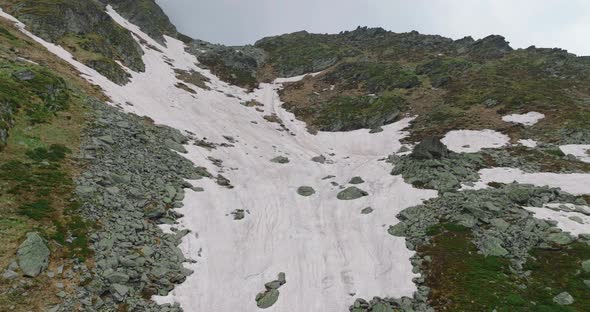 flying towards snowy rocky slope in the mountains