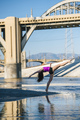 Side view of dancer, leg raised, bending over backwards in front of bridge, Los Angeles, California, - PhotoDune Item for Sale