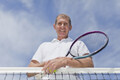 Older man leaning on tennis net - PhotoDune Item for Sale
