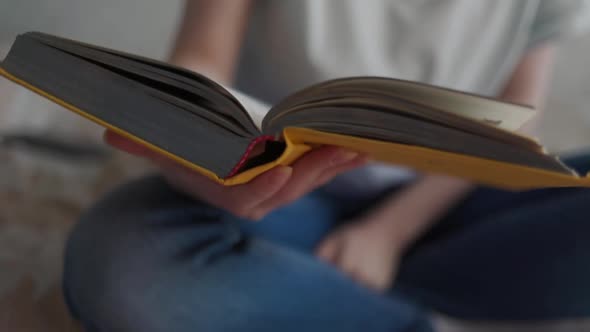 A young woman reads a book, puts it away, and takes out her smartphone, smiling as she types in it