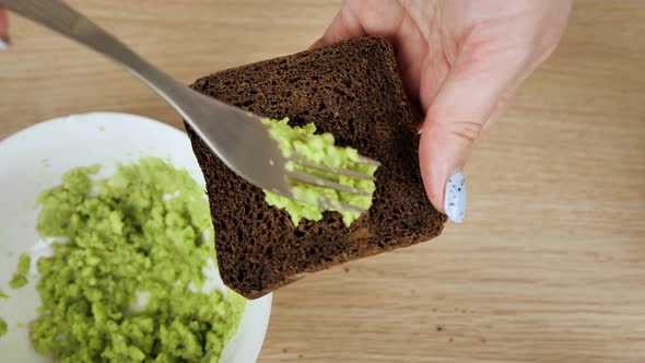 A Woman's Hand Takes a Sandwich From an Avocado and Guacamole Sandwich