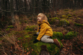 Blonde Child in Yellow Coat Climbing Mossy Stones in Autumn Forest - PhotoDune Item for Sale