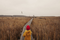 Girl in Yellow Coat and Red Hat Walking to the Bird Watch Tower, Holding a Reed and Looking Forward - PhotoDune Item for Sale