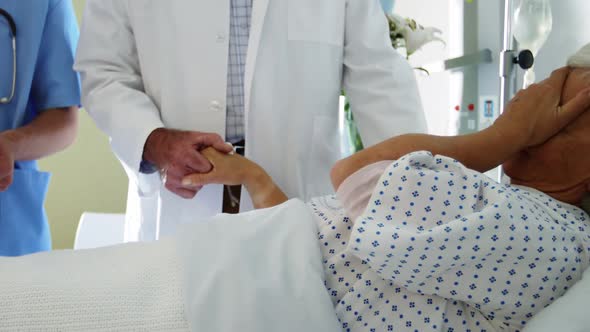 Doctor trying to console crying female senior patient on the bed