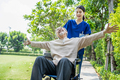 Caregiver doctor pushing elderly patient raising arm on wheelchair, enjoy hearth care activity. - PhotoDune Item for Sale