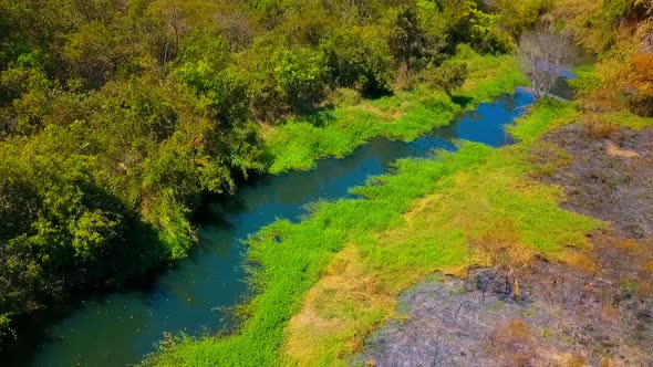 Slow descending aerial shot over a small colorful creek