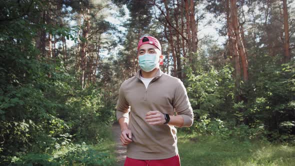 Asian Young Man are Jogging Outdoor in City Park and Wearing Protective Mask on Face for Stay in Fit