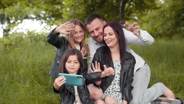 Positive Family Sitting Together on Soft Plaid Utdoors and Taking Selfie on