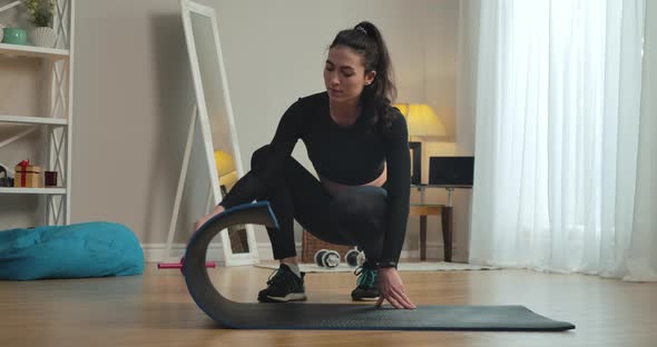 Confident Slim Caucasian Sportswoman Unrolling Exercise Mat at Home and Looking at Camera. Portrait