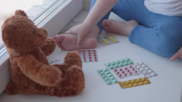 Toddler Sits on Windowsill and Plays with Scattering Pills Without Parent's Control. Dangerous