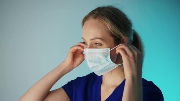 Young Pensive Caucasian Female Surgeon Putting on or Taking Off Her Face Mask