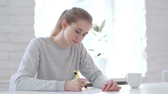 Young Woman Writing Documents in Office Paperwork