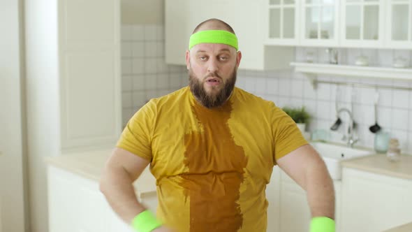 Tired Man in Yellow Sportswear Wipes Sweat From Forehead After Training at Home