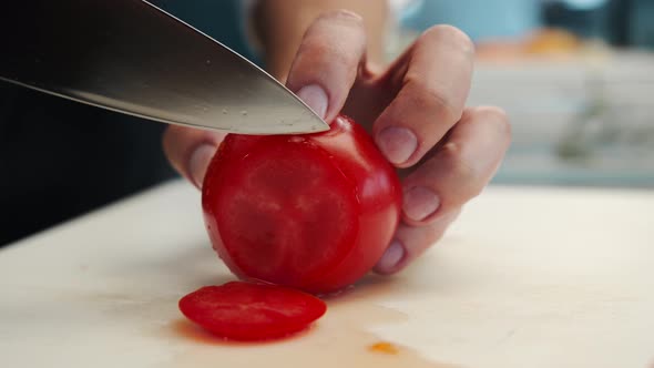 Professional restaurant kitchen, close-up: Chef cuts tomatoes with a knife