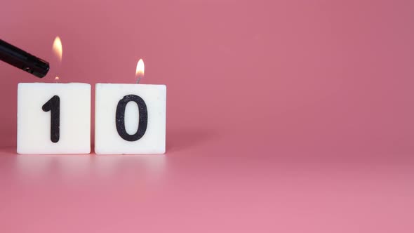 A square candle saying the number 10 being lit and blown out