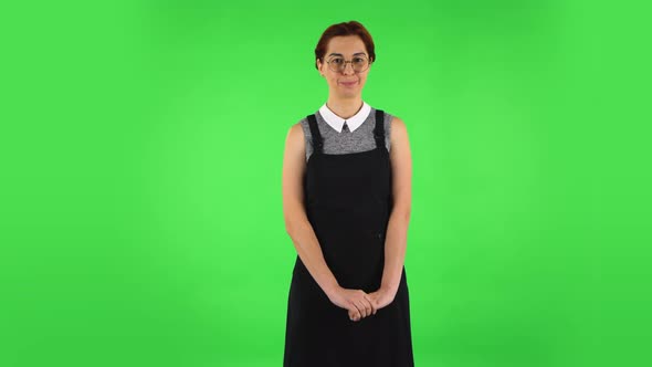 Funny Girl in Round Glasses Is Coquettishly Smiling While Looking at Camera. Green Screen