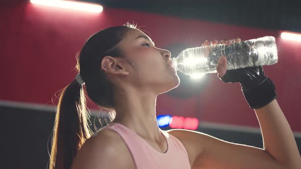 Asian active beautiful young girl athlete or sportswoman standing in fitness and drink water in gym