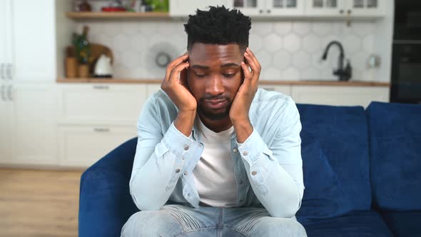 Unhappy AfricanAmerican Guy Sitting Alone at Home and Feels Despair