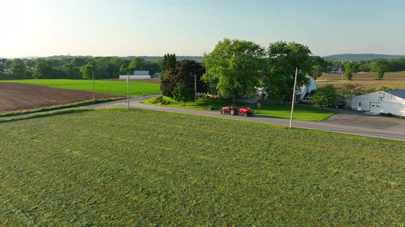 Aerial approach towards red tractor with baler attached. Beautiful spring day in Amish country.