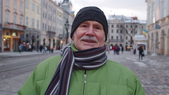 Portrait of Old Senior Man Tourist Smiling Looking at Camera in Winter City Center of Lviv Ukraine