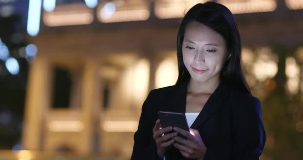 Businesswoman use of smart phone in city at night 