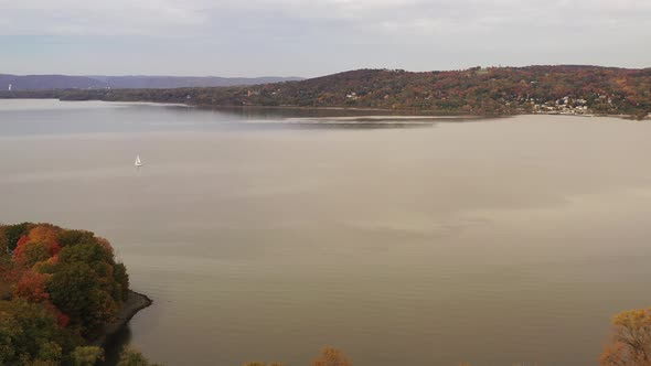 aerial drone dolly shot in towards a white sailboat in the Hudson River on a cloudy day at Croton Po