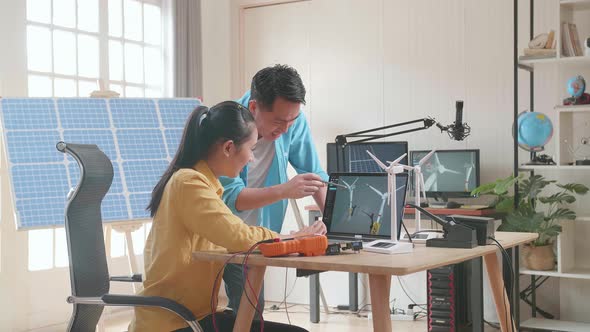 Asian Man And Woman Discuss About Work With Wind Turbine And Laptop Computer