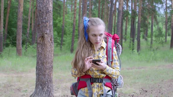 Woman with Backpack Looking for Destination Point in a GPS with a Mobile Phone.