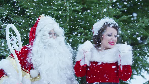 Santa Claus and Christmas girl enjoying the snowfall alt