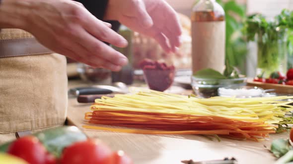 Male Cook Throwing Bunch of Uncooked Spaghetti on Table