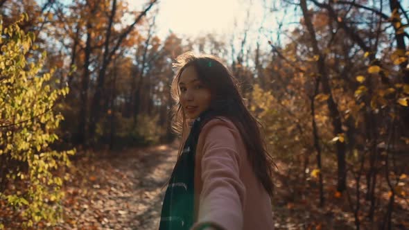 Charming Girl Is Pulling Hand of Cameraman in Sunny Autumn Forest, Close-up View