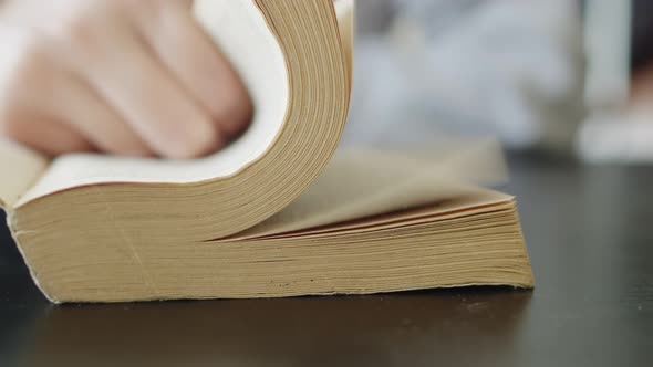 Hand turns over many pages of the book, slide. Close-up, a woman's hand turns the pages of a book.