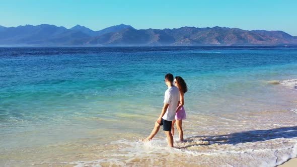 Young couple sunbathing on paradise seashore beach journey by aqua blue sea with bright sand backgro