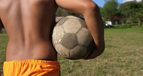 Rural Boy Walking And Holding Soccer Ball