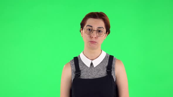 Portrait of Funny Girl in Round Glasses Upset and Shrugging. Green Screen