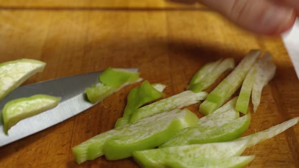 A close-up of a green radish being sliced in julienne on kitchen board