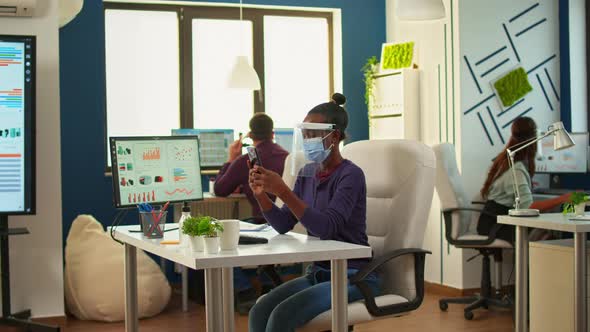 Black Woman Browsing on Smartphone Sitting in New Normal Office