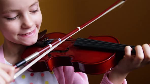 Schoolgirl playing violin in classroom at school