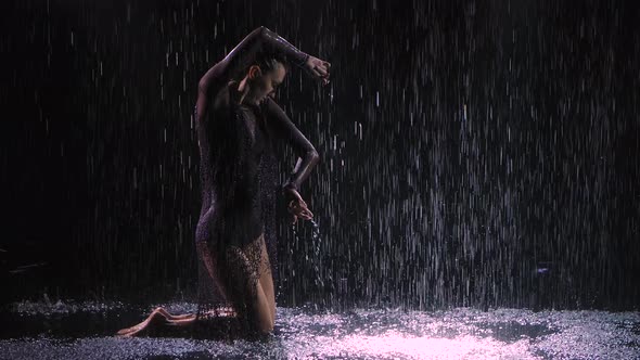 Against a Black Background in the Rain, a Young Couple of Ballroom Dancer Are Passionately Dancing