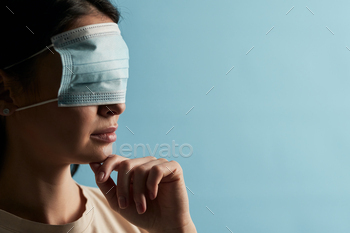protective mask on her eyes on a blue background. Copy space. Quarantine, epidemic concept