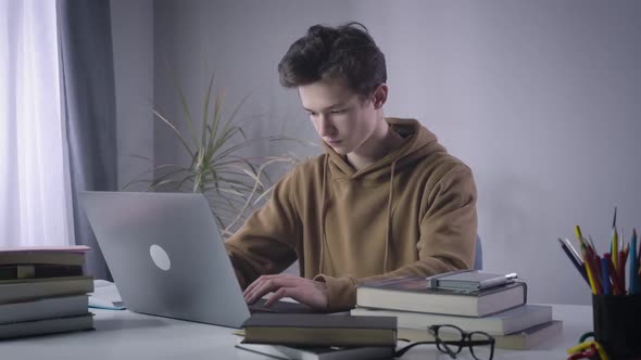 Unhappy Caucasian Boy Leaning Back From Laptop and Taking Head in Hands. Portrait of Stressed alt